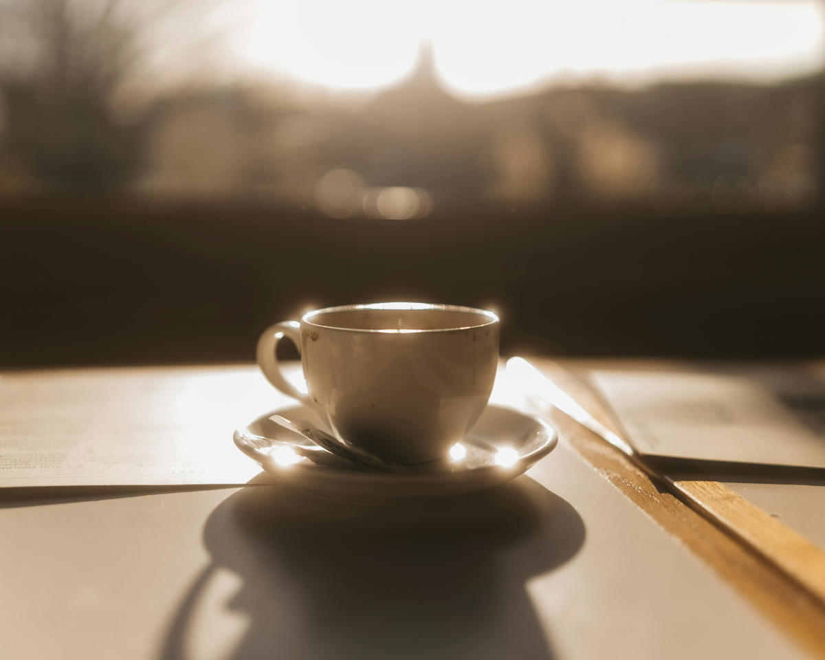 Editorial photograph of a person holding a cup of Eighth House Solar Mushroom Coffee in soft, low light